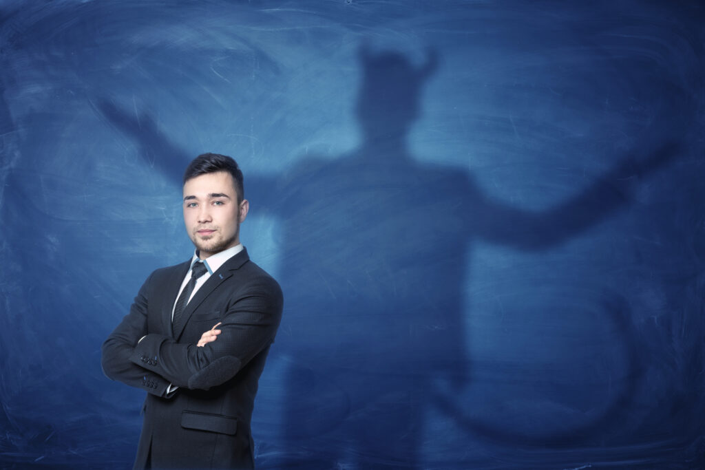 Businessman standing with hands across and his shadow on blue Businessman standing with hands across and his shadow on blue