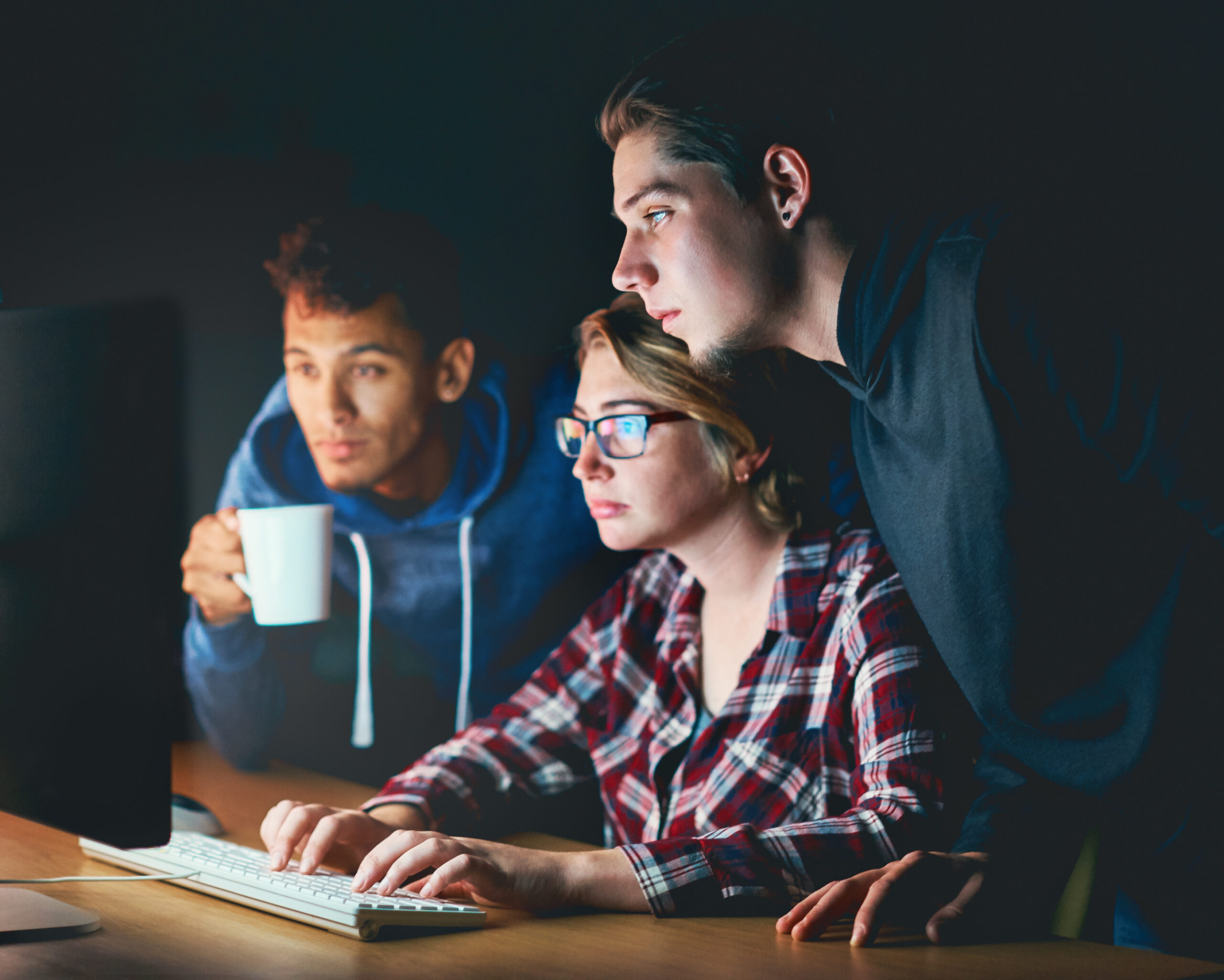 Three young people working late on a computer